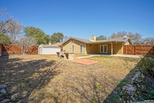 back of house with an outbuilding, a patio, a fenced backyard, a storage shed, and french doors