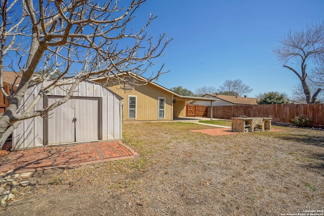 view of yard featuring a storage shed, a patio, an outdoor structure, and fence private yard