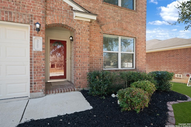 property entrance with a garage and brick siding