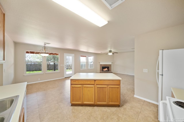 kitchen with a ceiling fan, open floor plan, freestanding refrigerator, light countertops, and a fireplace