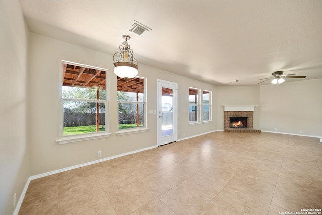 unfurnished living room with baseboards, a brick fireplace, visible vents, and a healthy amount of sunlight