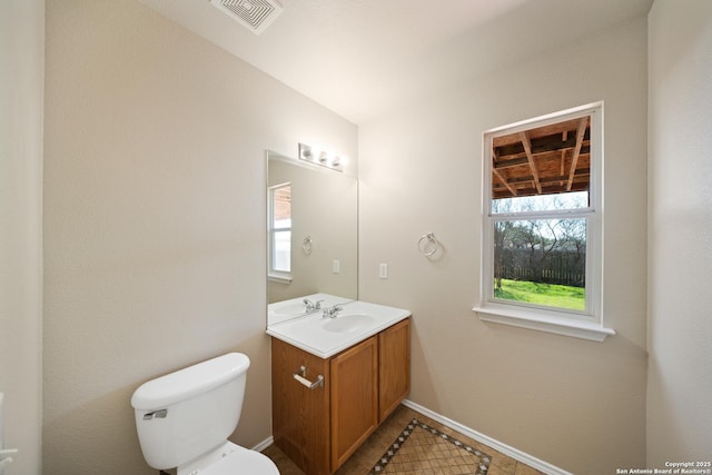 half bath featuring baseboards, visible vents, vanity, and toilet