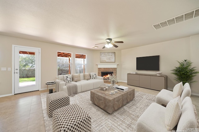 living room with a fireplace, light tile patterned floors, visible vents, a ceiling fan, and baseboards