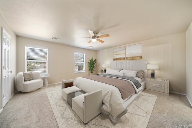 bedroom featuring baseboards, visible vents, a ceiling fan, light colored carpet, and a textured ceiling