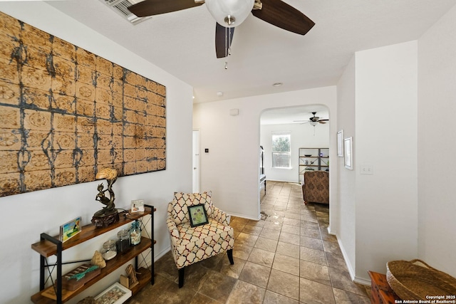 sitting room with arched walkways, visible vents, a ceiling fan, and baseboards