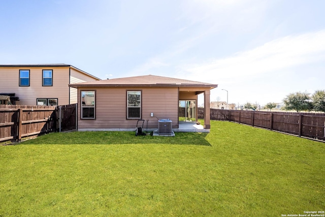 rear view of house with central air condition unit, a fenced backyard, a yard, and a patio