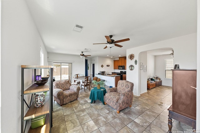 living room with arched walkways, a healthy amount of sunlight, ceiling fan, and visible vents