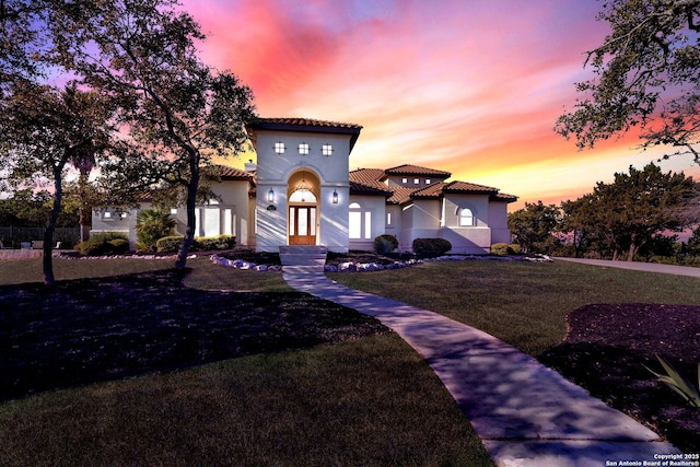 mediterranean / spanish-style house featuring a tiled roof, a front lawn, and stucco siding