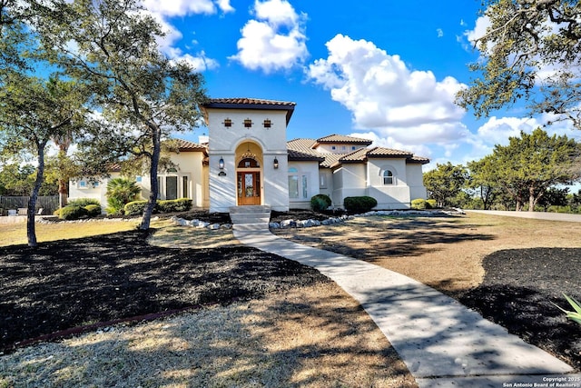 mediterranean / spanish home featuring a tile roof and stucco siding