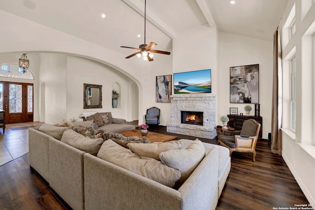 living area with dark wood-style floors, beamed ceiling, a stone fireplace, high vaulted ceiling, and recessed lighting