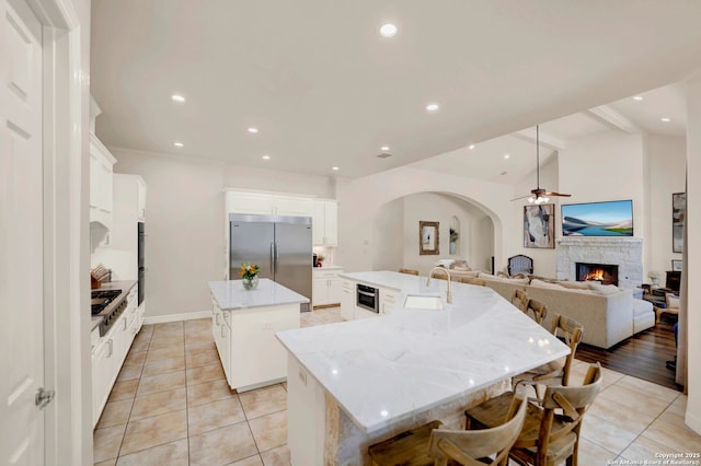 kitchen featuring light tile patterned floors, a spacious island, vaulted ceiling, a sink, and built in fridge