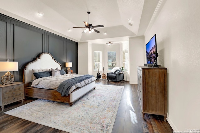 bedroom with baseboards, a tray ceiling, dark wood finished floors, and a ceiling fan