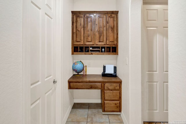 home office featuring baseboards, built in study area, and light tile patterned flooring