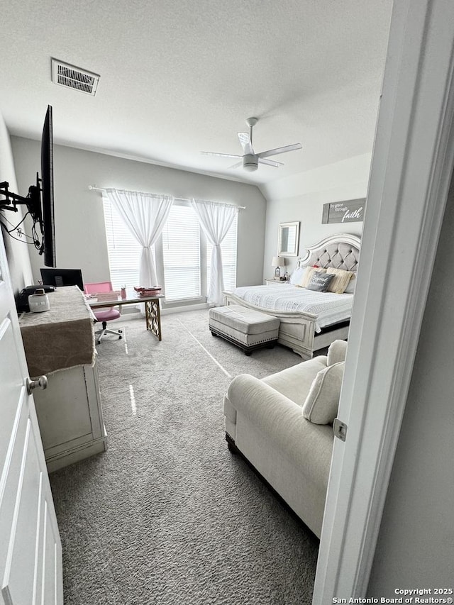 bedroom with a textured ceiling, ceiling fan, carpet floors, visible vents, and vaulted ceiling