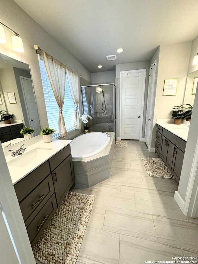 full bathroom featuring a garden tub, two vanities, a sink, visible vents, and a shower stall