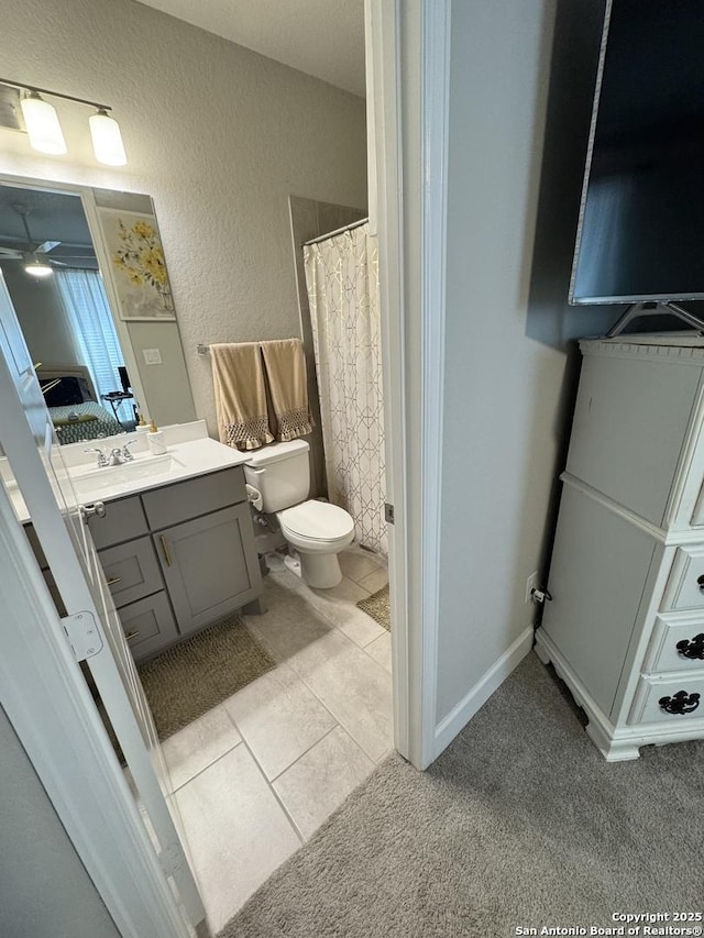 full bath with connected bathroom, a textured wall, toilet, tile patterned floors, and vanity