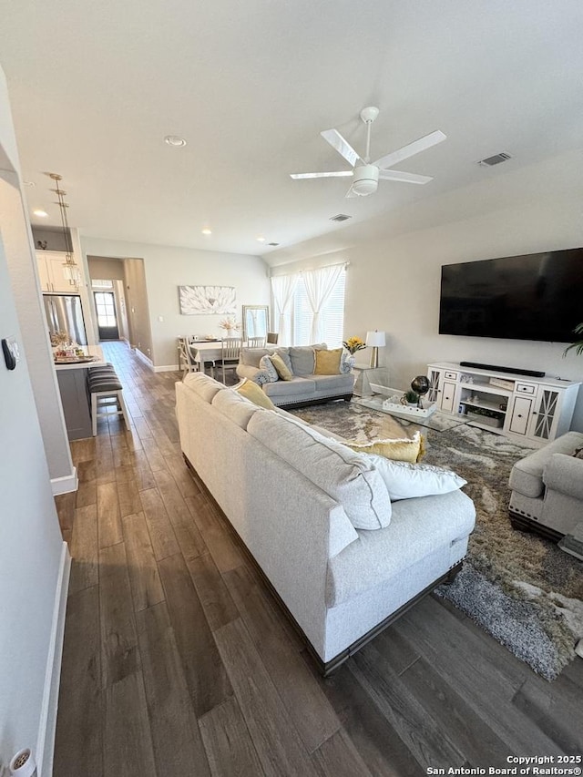 living room with dark wood-style floors, ceiling fan, visible vents, and a wealth of natural light