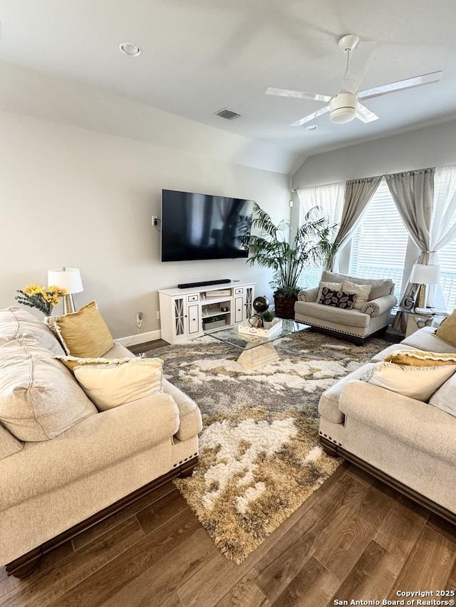 living area featuring a ceiling fan, visible vents, baseboards, and wood finished floors