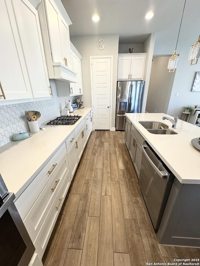 kitchen with stainless steel appliances, premium range hood, a sink, decorative backsplash, and dark wood finished floors