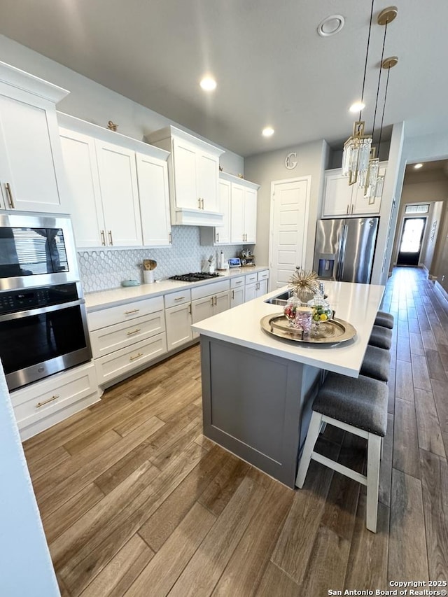 kitchen featuring white cabinets, dark wood-style floors, appliances with stainless steel finishes, and decorative backsplash