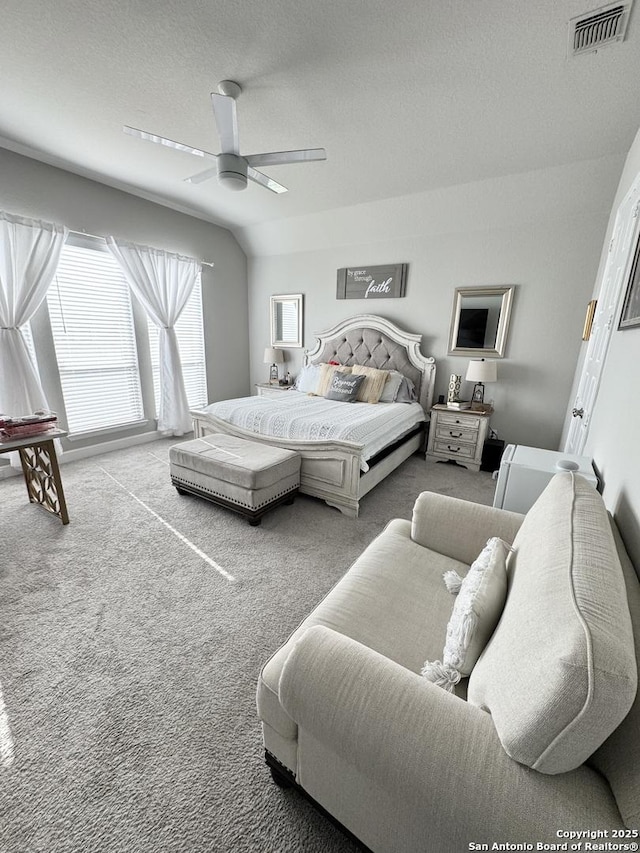 bedroom with carpet floors, visible vents, vaulted ceiling, a textured ceiling, and ceiling fan