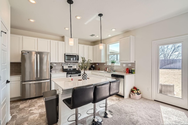 kitchen with stainless steel appliances, a sink, light countertops, and white cabinets