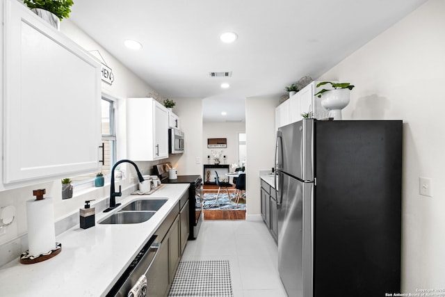 kitchen with stainless steel appliances, light countertops, visible vents, white cabinetry, and a sink