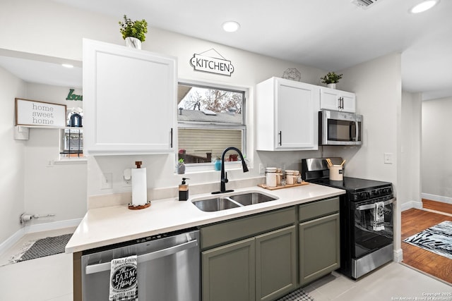 kitchen with appliances with stainless steel finishes, light countertops, a sink, and recessed lighting