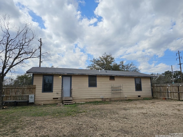 rear view of house with entry steps, crawl space, and fence