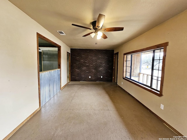 empty room with concrete flooring, visible vents, ceiling fan, and baseboards