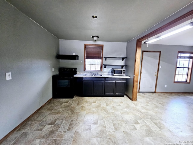 kitchen featuring open shelves, light countertops, stainless steel microwave, black range with electric stovetop, and a sink