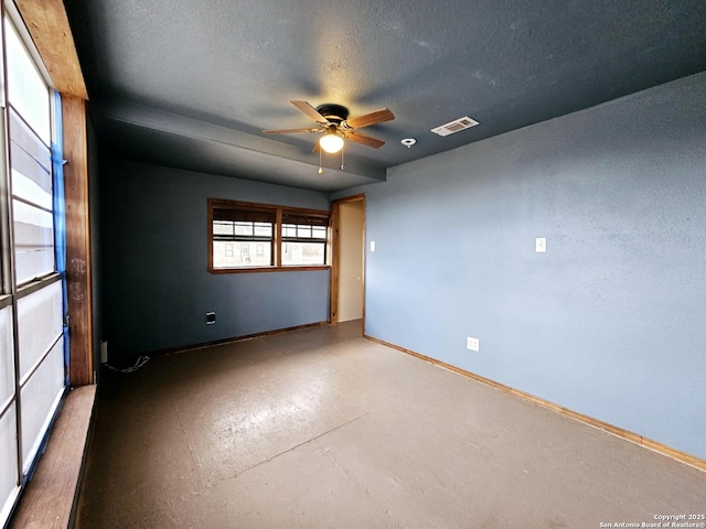 empty room featuring visible vents, finished concrete floors, a ceiling fan, a textured ceiling, and baseboards