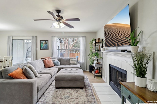 living area featuring a fireplace, tile patterned flooring, and a ceiling fan