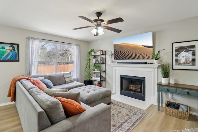 living room with ceiling fan, a fireplace, wood finished floors, and baseboards