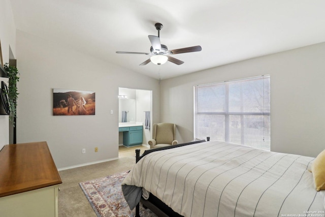 bedroom featuring baseboards, light colored carpet, ensuite bath, ceiling fan, and vaulted ceiling