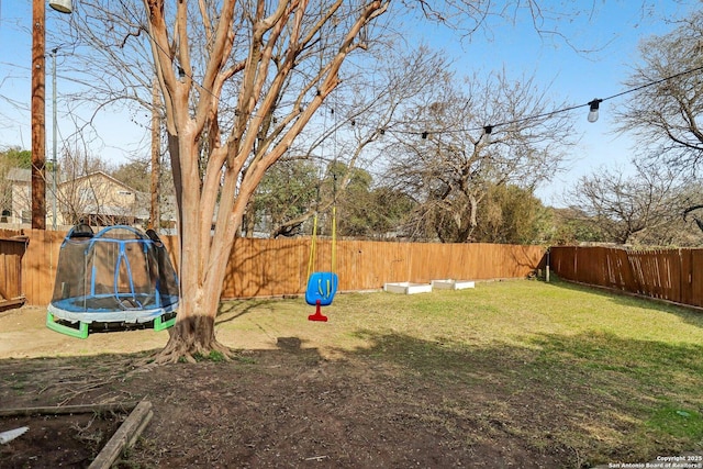 view of yard featuring a trampoline and a fenced backyard