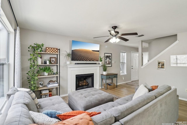 living room with visible vents, ceiling fan, wood finished floors, a tile fireplace, and baseboards