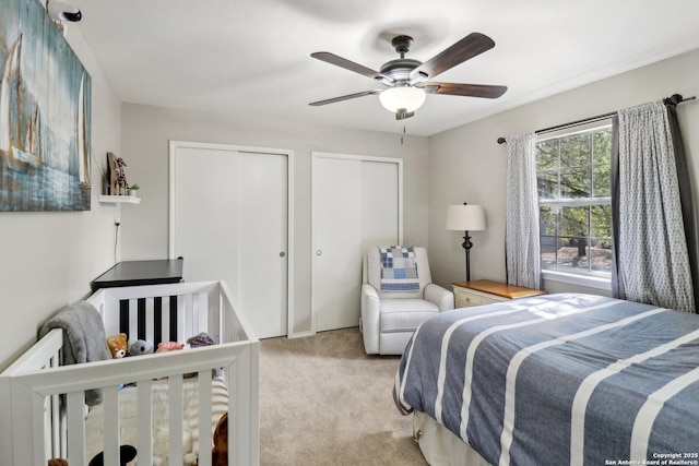 bedroom with carpet, ceiling fan, and multiple closets