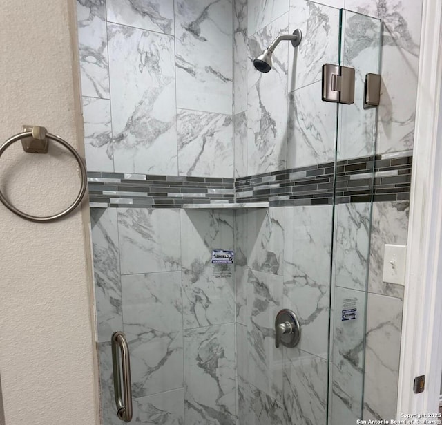 bathroom featuring a textured wall and a shower stall