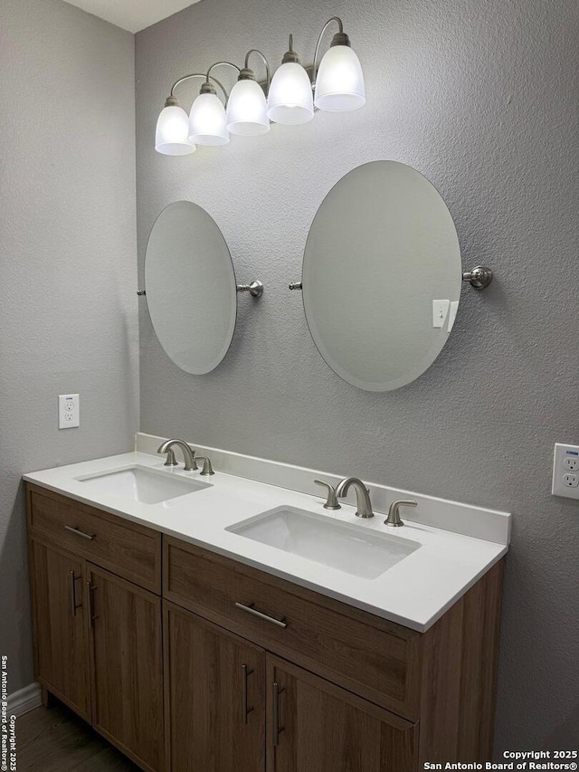 full bathroom featuring a textured wall, a sink, and double vanity