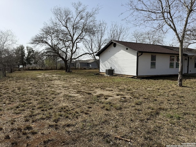 view of side of home featuring cooling unit and a yard