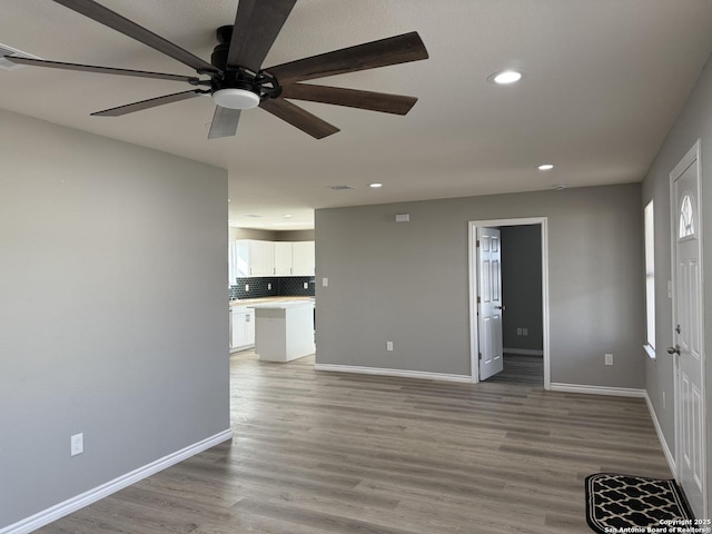 unfurnished living room with recessed lighting, ceiling fan, light wood-style flooring, and baseboards