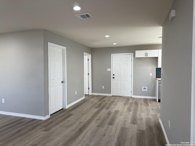 spare room with recessed lighting, wood finished floors, visible vents, and baseboards