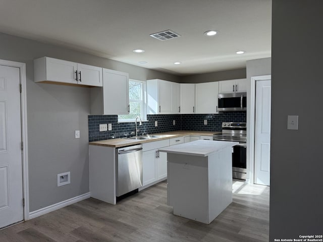 kitchen featuring appliances with stainless steel finishes, white cabinets, visible vents, and a sink