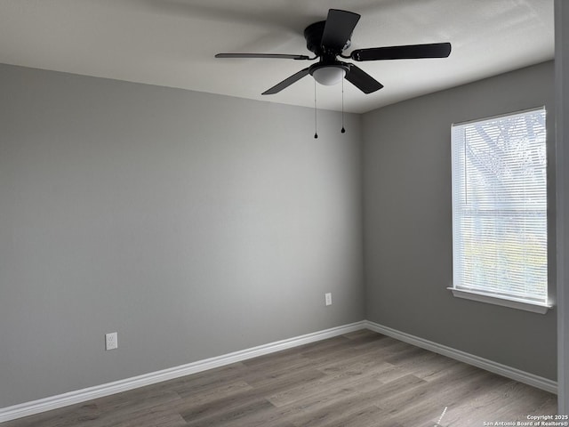 spare room with baseboards and wood finished floors