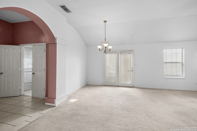 carpeted spare room featuring a chandelier, lofted ceiling, visible vents, and arched walkways