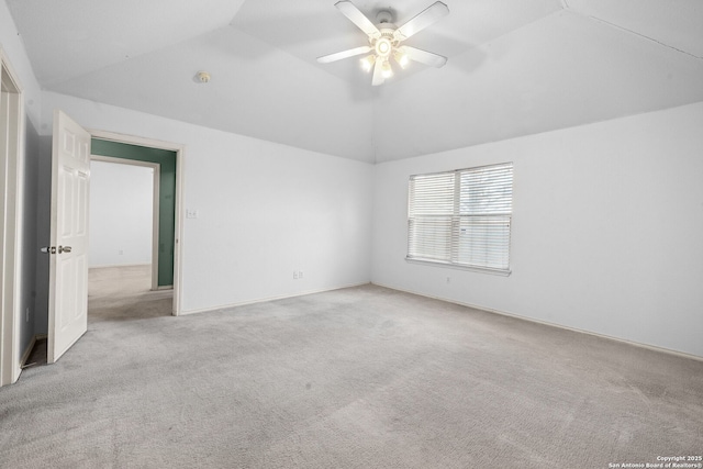 empty room with lofted ceiling, ceiling fan, and carpet flooring