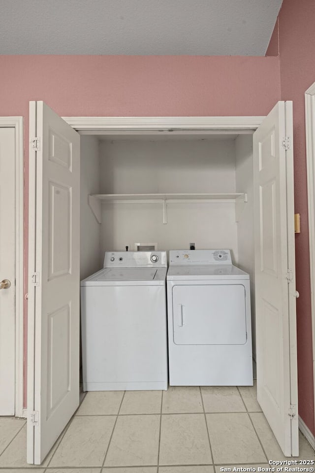 clothes washing area featuring laundry area, washing machine and dryer, and light tile patterned floors