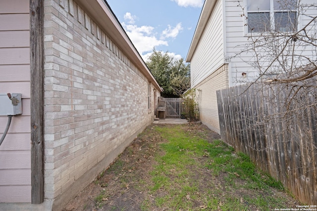 view of side of property with brick siding and fence