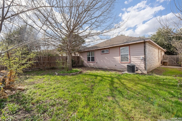 exterior space featuring cooling unit, brick siding, a lawn, and fence